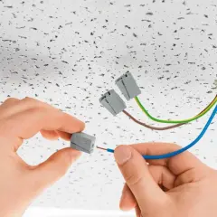 Ręce montują przewody do złączek elektrycznych. To szybkie i bezpieczne rozwiązanie, czy to wago czy kostka, ułatwia instalację.