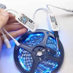 Ręka trzymająca kontroler Wi-Fi do taśmy LED. Dowiedz się, jak zresetować pilot do ledów, skanując kod QR.