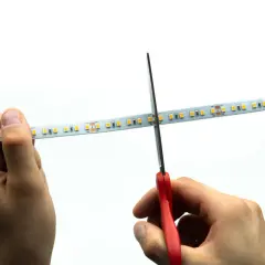 Ręce tną taśmę LED nożyczkami. Czy taśmę LED można ciąć w dowolnym miejscu? Tak, w zaznaczonych miejscach.