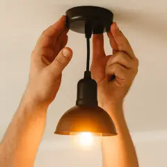 Ręce montują żyrandol z migającą żarówką.