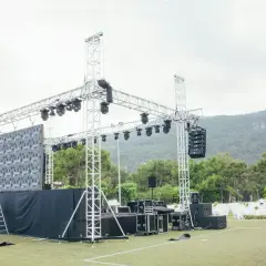 Scena z ekranem LED i różnymi rodzajami oświetlenia scenicznego, głośnikami i konstrukcjami aluminiowymi, gotowa na wydarzenie.