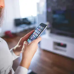 Kobieta steruje urządzeniami w swoim domu za pomocą smartfona, tworząc **smart life** z aplikacją **Tuya**.