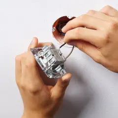 Instalacja podwójnego włącznika światła 2 kable. Dłonie montują mechanizm w puszce, podłączając przewody.