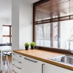 Nowoczesne oświetlenie nad oknem w kuchni, z widokiem na balkon i jadalnię.