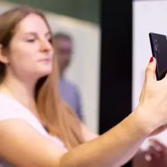 Kobieta z długimi blond włosami trzyma smartfon, na którym widać **aplikację Tuya po polsku**.