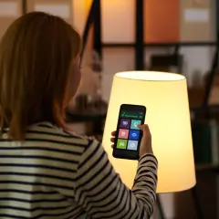 Kobieta steruje domem przez aplikację na telefonie. To smart life po polsku, wygoda i nowoczesność w zasięgu ręki.