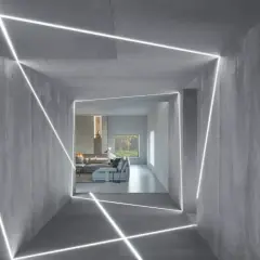Nowoczesny korytarz z betonowymi ścianami, gdzie linie LED tworzą geometryczne wzory. Inspiracja, jak zamontować oświetlenie LED w witrynie, by nadać jej futurystyczny wygląd.