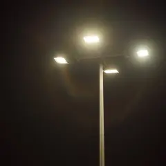 Słup oświetleniowy z czterema lampami LED, które rozświetlają noc. Widać tęczowe refleksy, jakby porównanie lampa sodowa vs led.