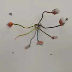 Sufit z instalacją elektryczną. Widać kilka przewodów, w tym jeden brązowy, połączonych złączkami.