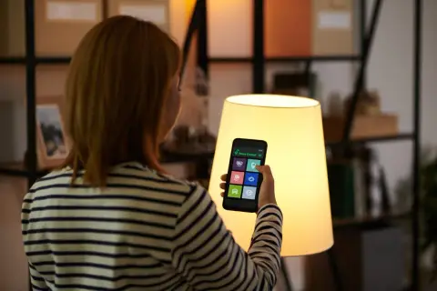 Kobieta steruje domem przez aplikację na telefonie. To smart life po polsku, wygoda i nowoczesność w zasięgu ręki.