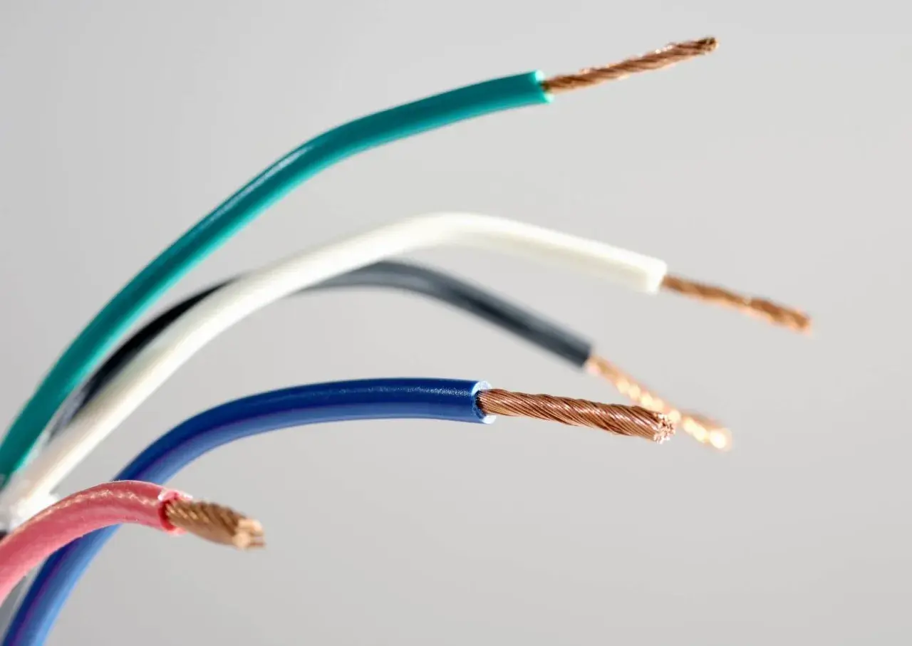 Pięć kolorowych kabli elektrycznych: zielony, biały, czarny, niebieski i różowy, z odsłoniętymi miedzianymi żyłami.