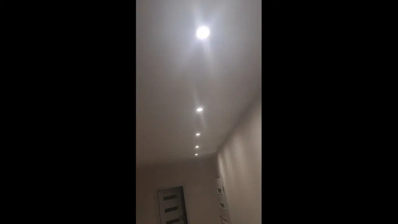 W korytarzu widać rząd wbudowanych w sufit lamp, które tworzą migające światło.