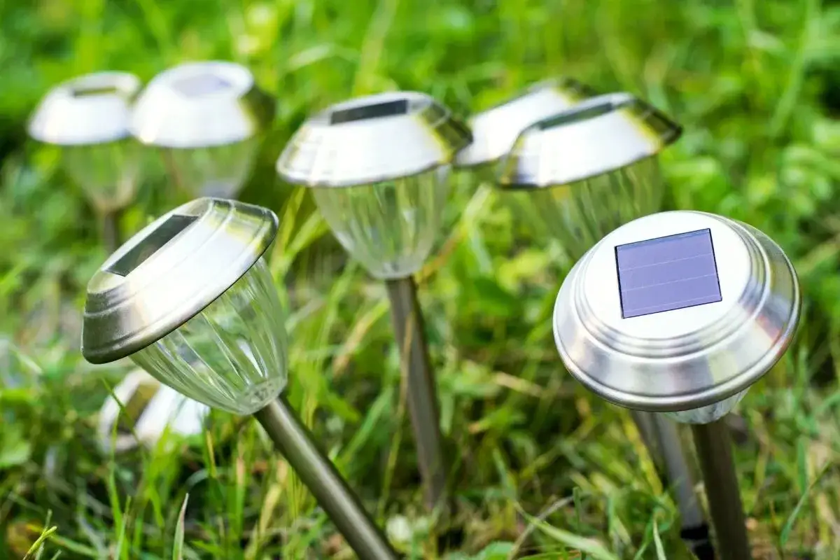 Kilka lamp solarnych w trawie. Zastanawiasz się, dlaczego lampki solarne nie świecą? Może panel słoneczny jest brudny lub uszkodzony.
