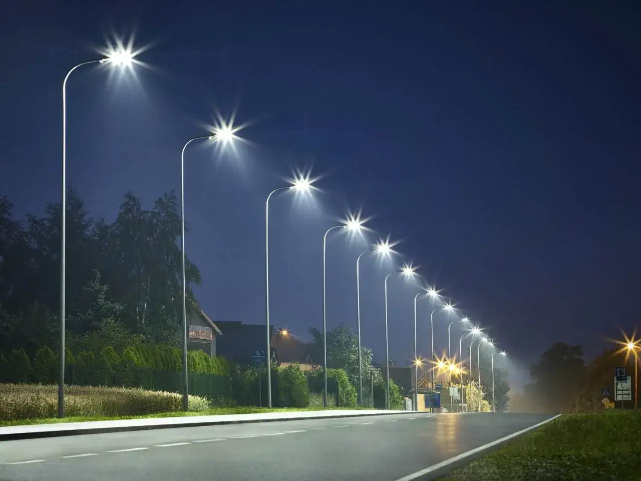 Rząd nowoczesnych lamp miejskich oświetla pustą drogę nocą, tworząc magiczną atmosferę.